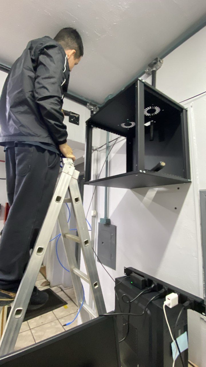 Técnico da Linkcore instalando rack de rede na parede de uma escola